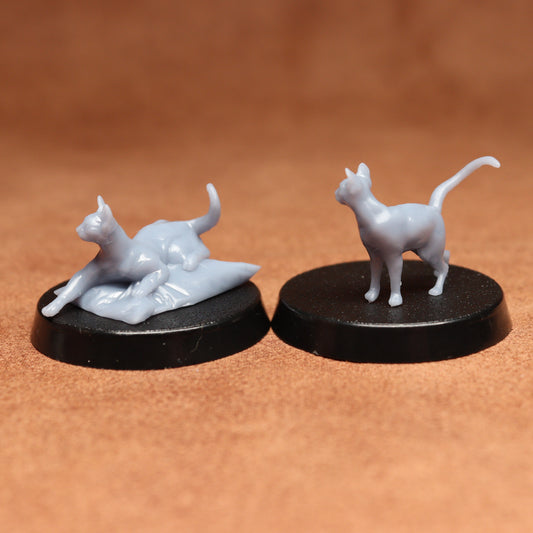 Two white cat figurines on black bases against a brown background