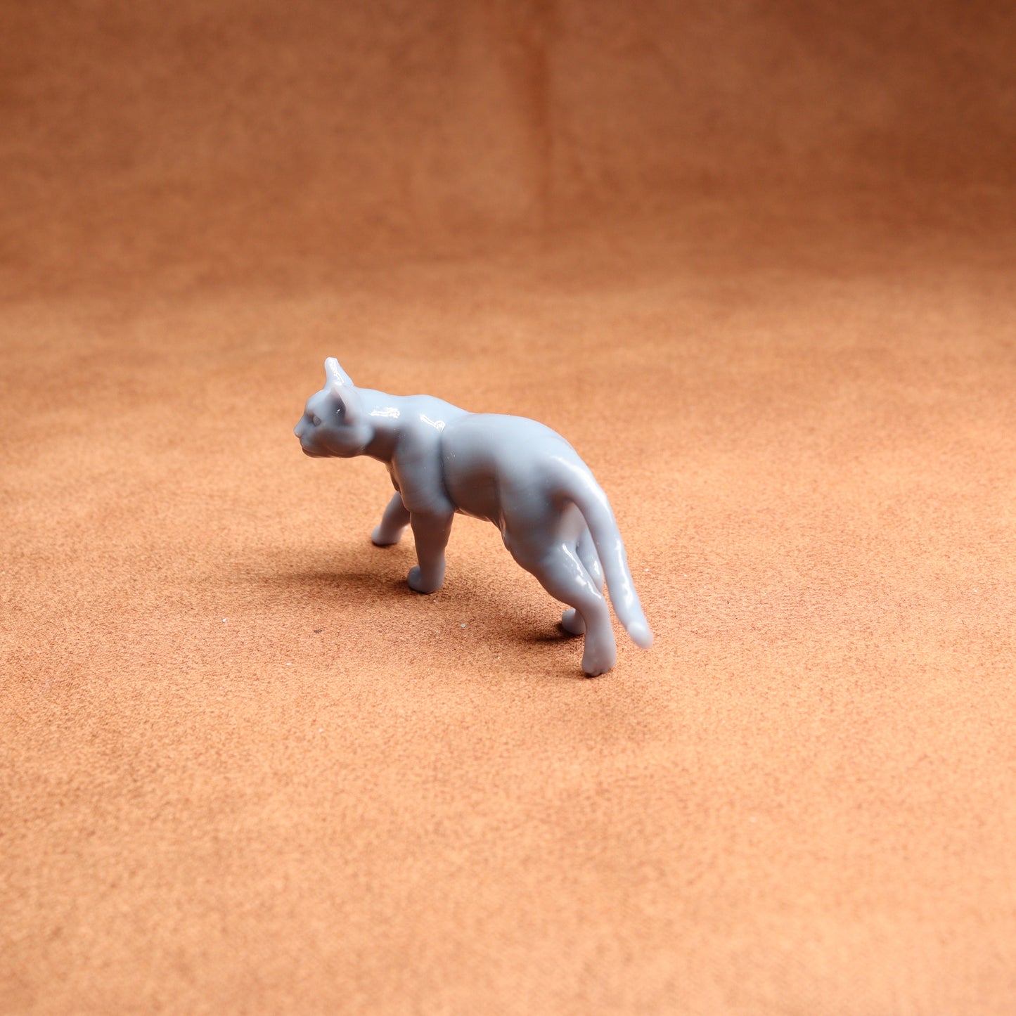 Small white cat figurine on a brown surface