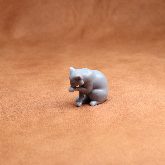 Small gray cat figurine on a brown surface