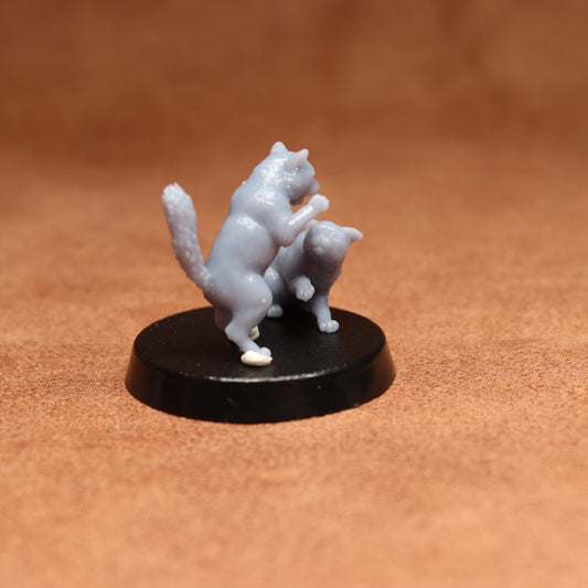 grey resin miniature cat figure on a black base with a brown background
