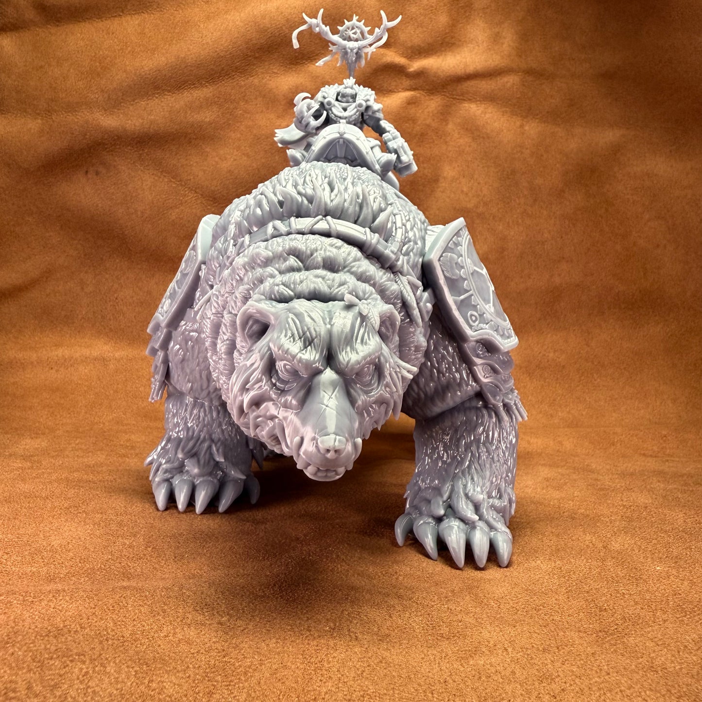 Fantasy figurine of a large creature with a smaller figure on its back against a brown fabric background