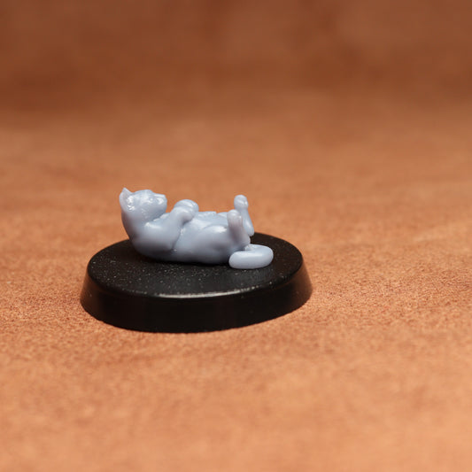 grey cat resin miniature on a black base on a brown background.