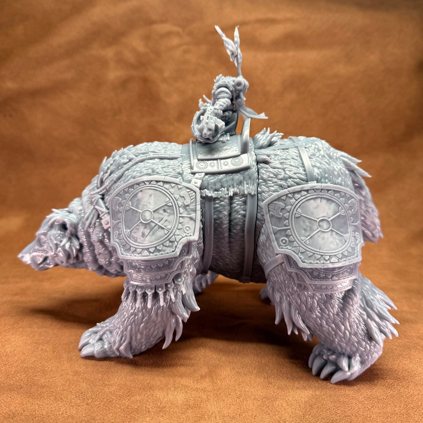 detailed figurine of a bear-like creature with armor and a rider on a brown background
