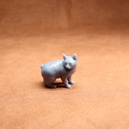 Small gray cat figurine on a brown surface