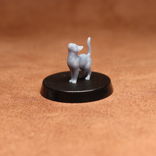 Small gray cat figurine on a black round base against a brown background