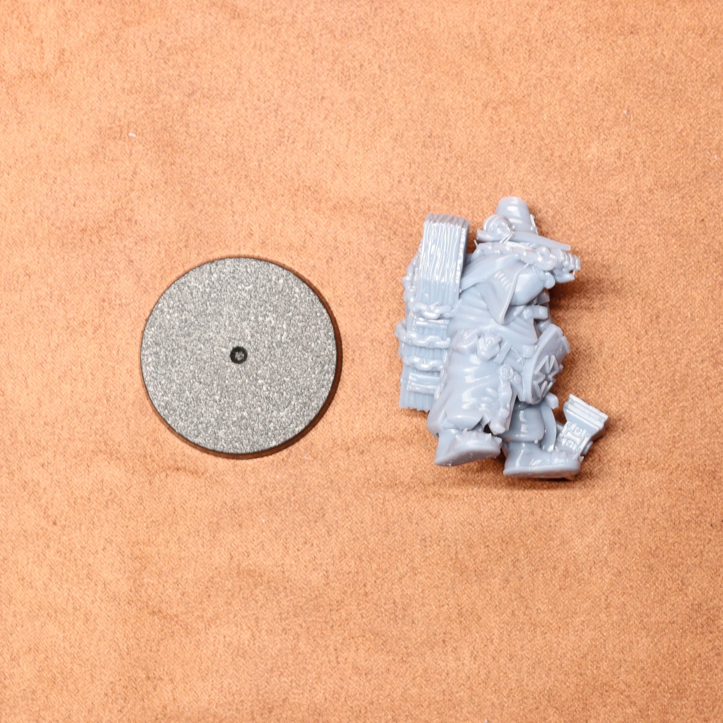 Small figurine and round metallic object on a beige surface