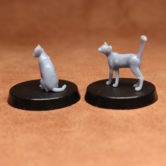 Two miniature cat figurines on black bases against a brown background