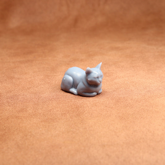 Small gray cat figurine on a brown surface