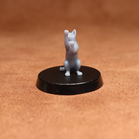 grey resin miniature cat figure on a black base with a brown background