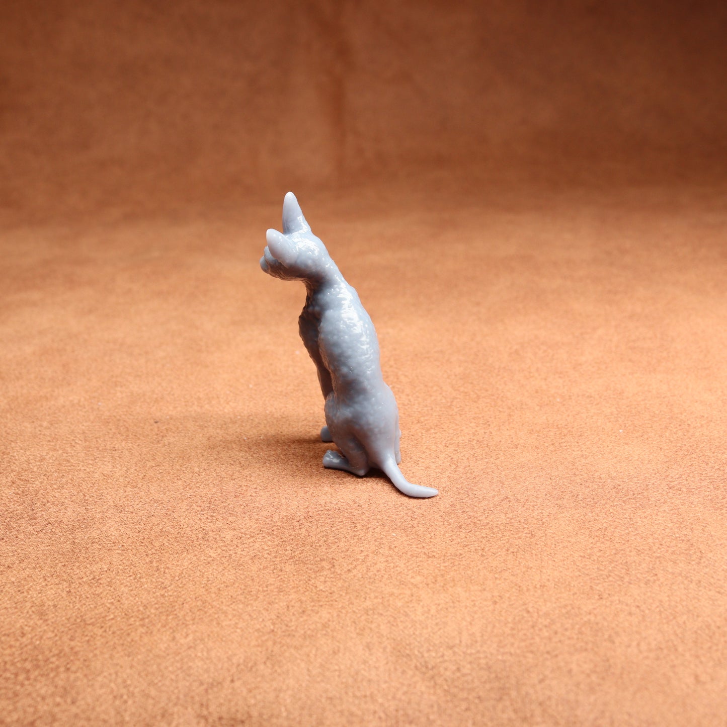 Small gray cat figurine on a brown surface
