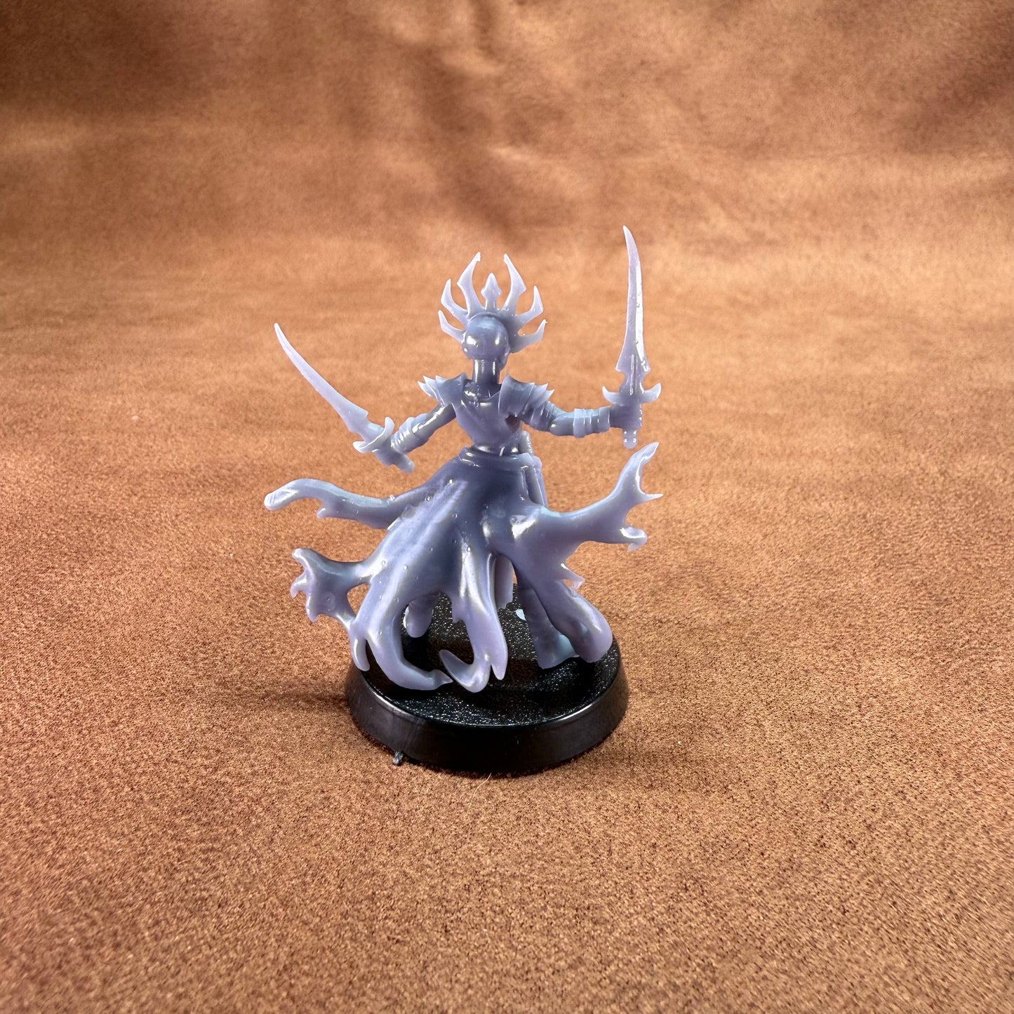 Fantasy figurine with a crown and two swords on a brown surface