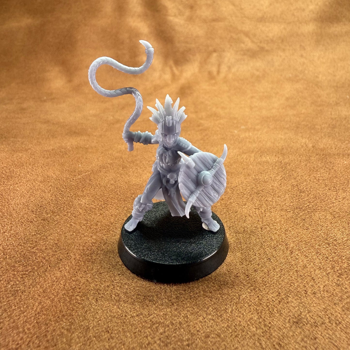 Gray fantasy figurine on a black base against a brown textured background