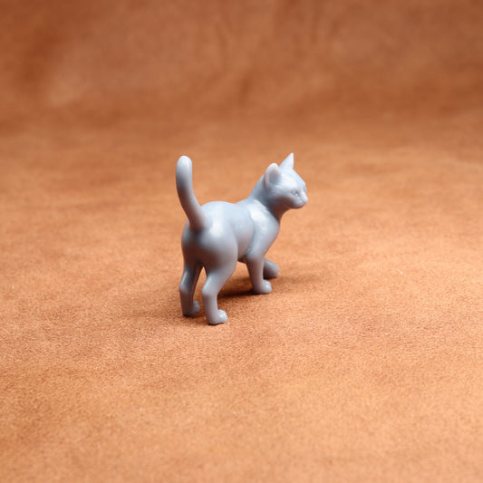 Small gray cat figurine on a brown surface