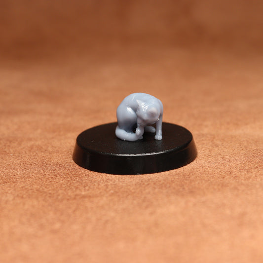 grey resin miniature cat figure on a black base with a brown background
