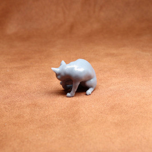 grey resin miniature cat figure on a brown surface