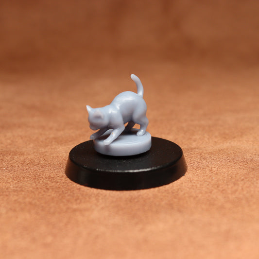 grey resin miniature cat figure on a black base with a brown background