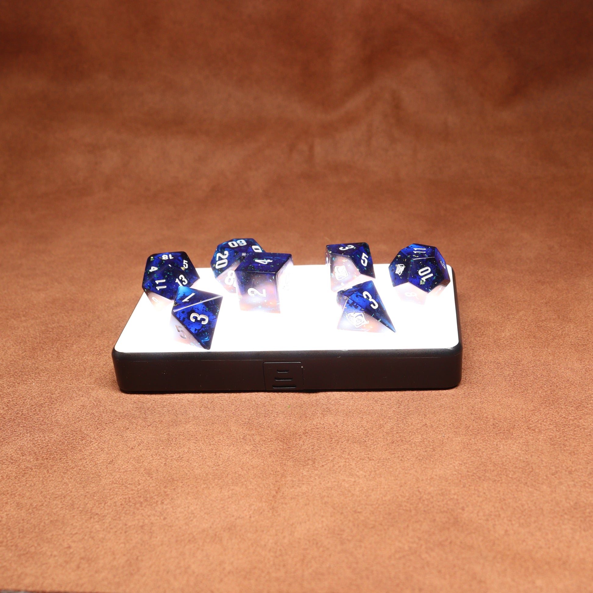 Set of blue polyhedral dice on a white tray against a brown background