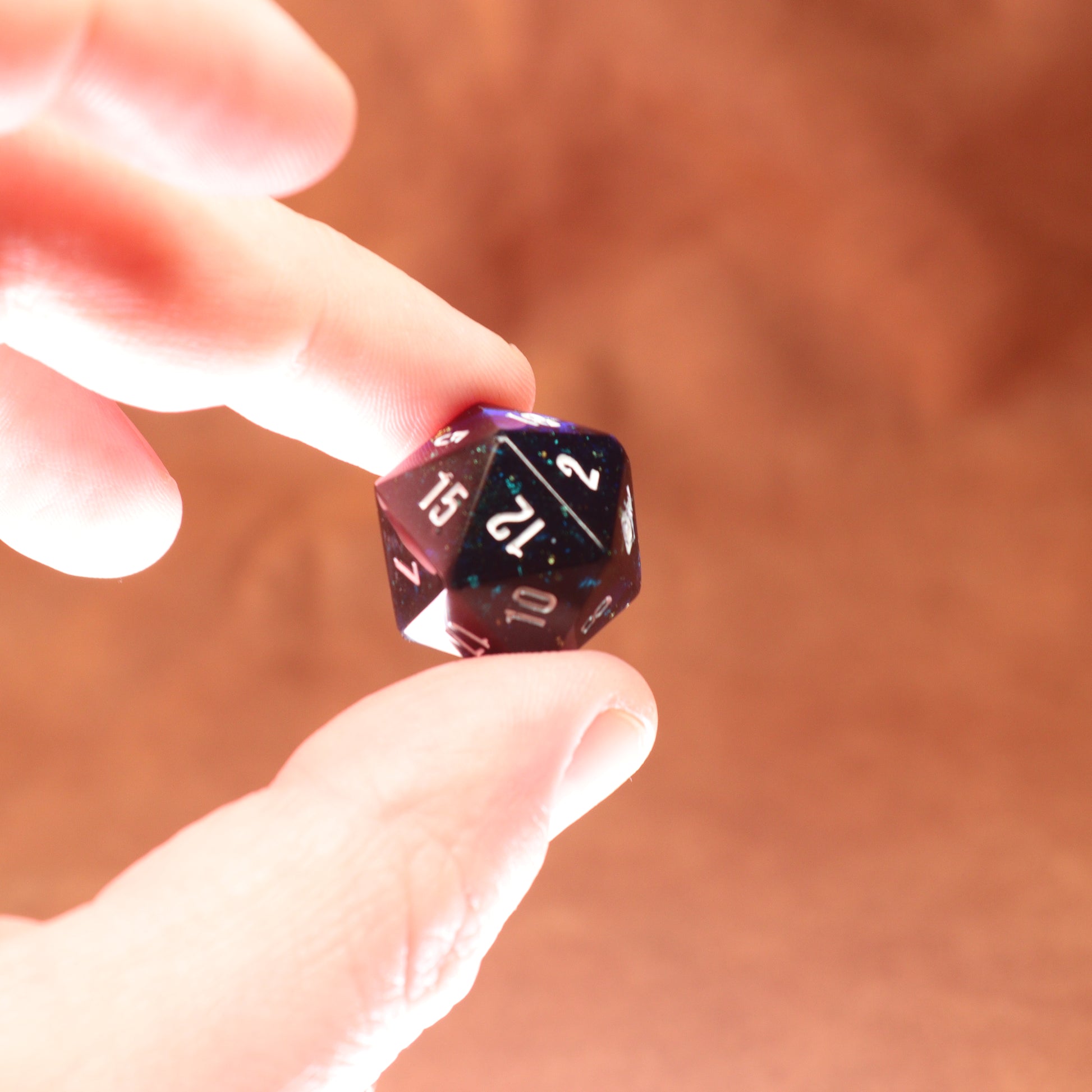 Hand holding a 20-sided die against a blurred background