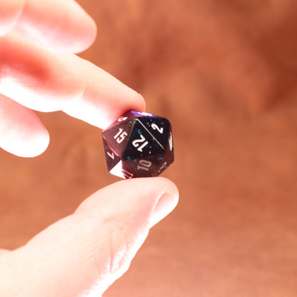 Hand holding a 20-sided die against a blurred background