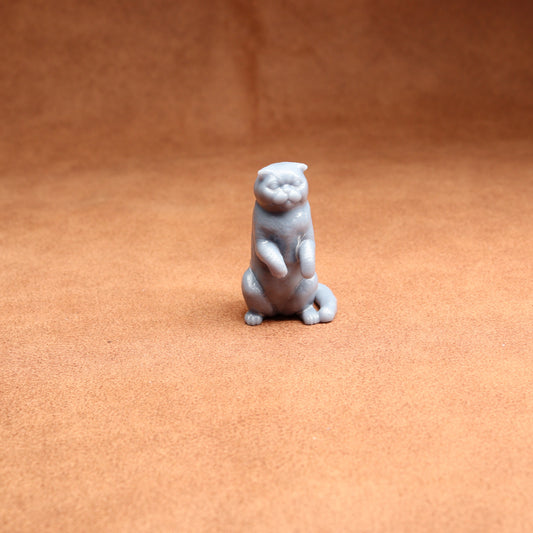 Small gray cat figurine on a brown surface