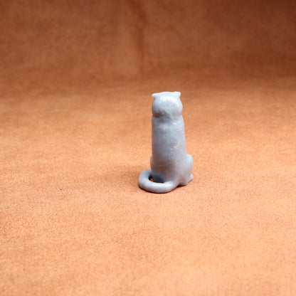 Small white ceramic cat figurine on a brown surface
