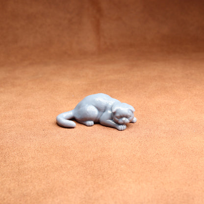 Small gray figurine of a cat on a brown surface