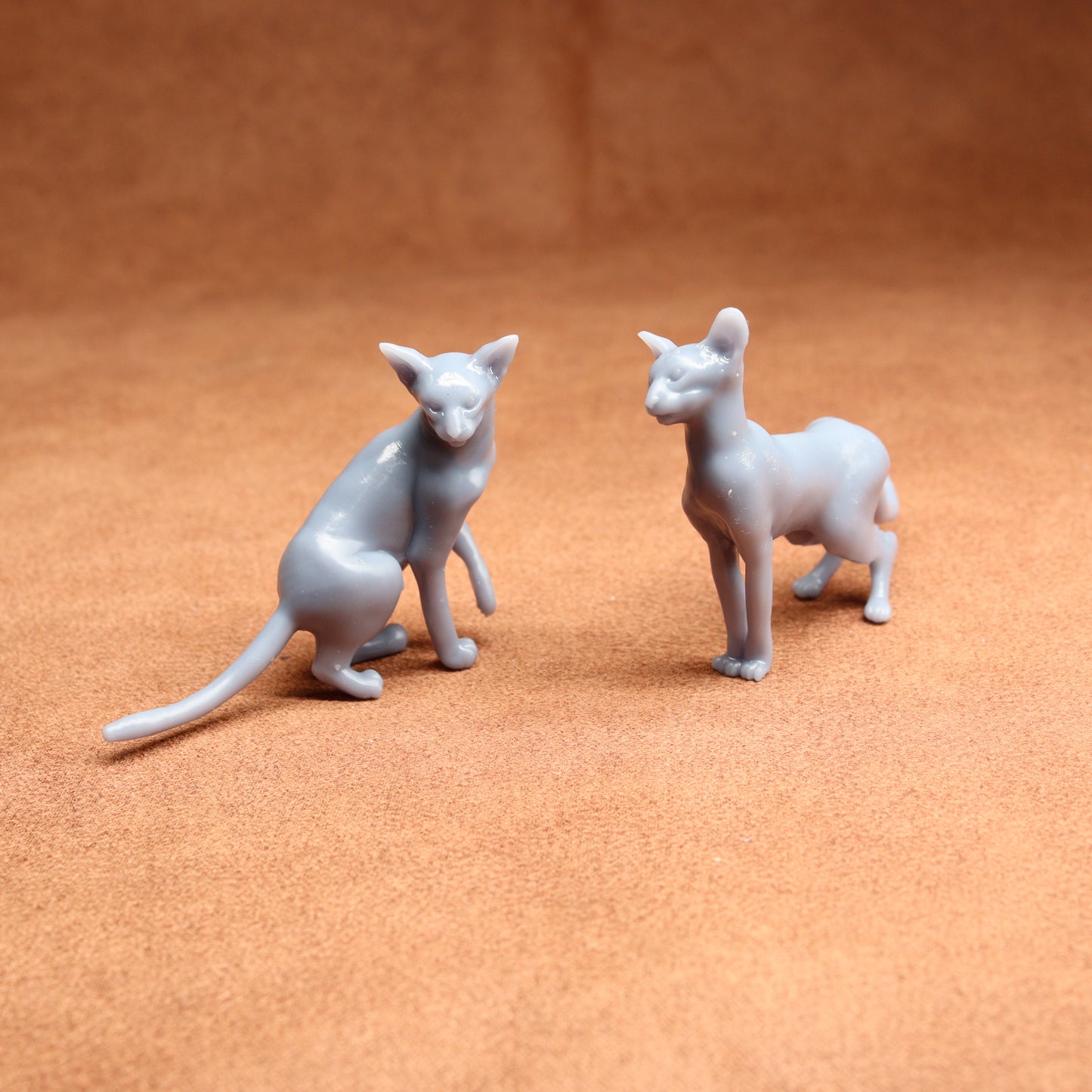 Two gray cat figurines on a brown surface
