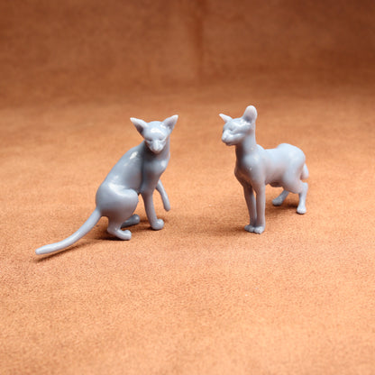 Two gray cat figurines on a brown surface