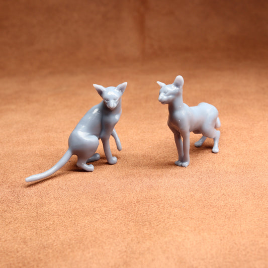 Two gray cat figurines on a brown surface