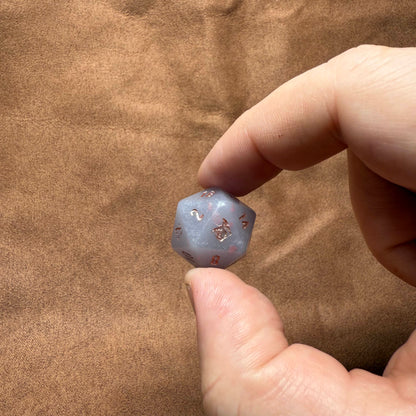 Hand holding a small blue crystal with star patterns against a brown fabric background
