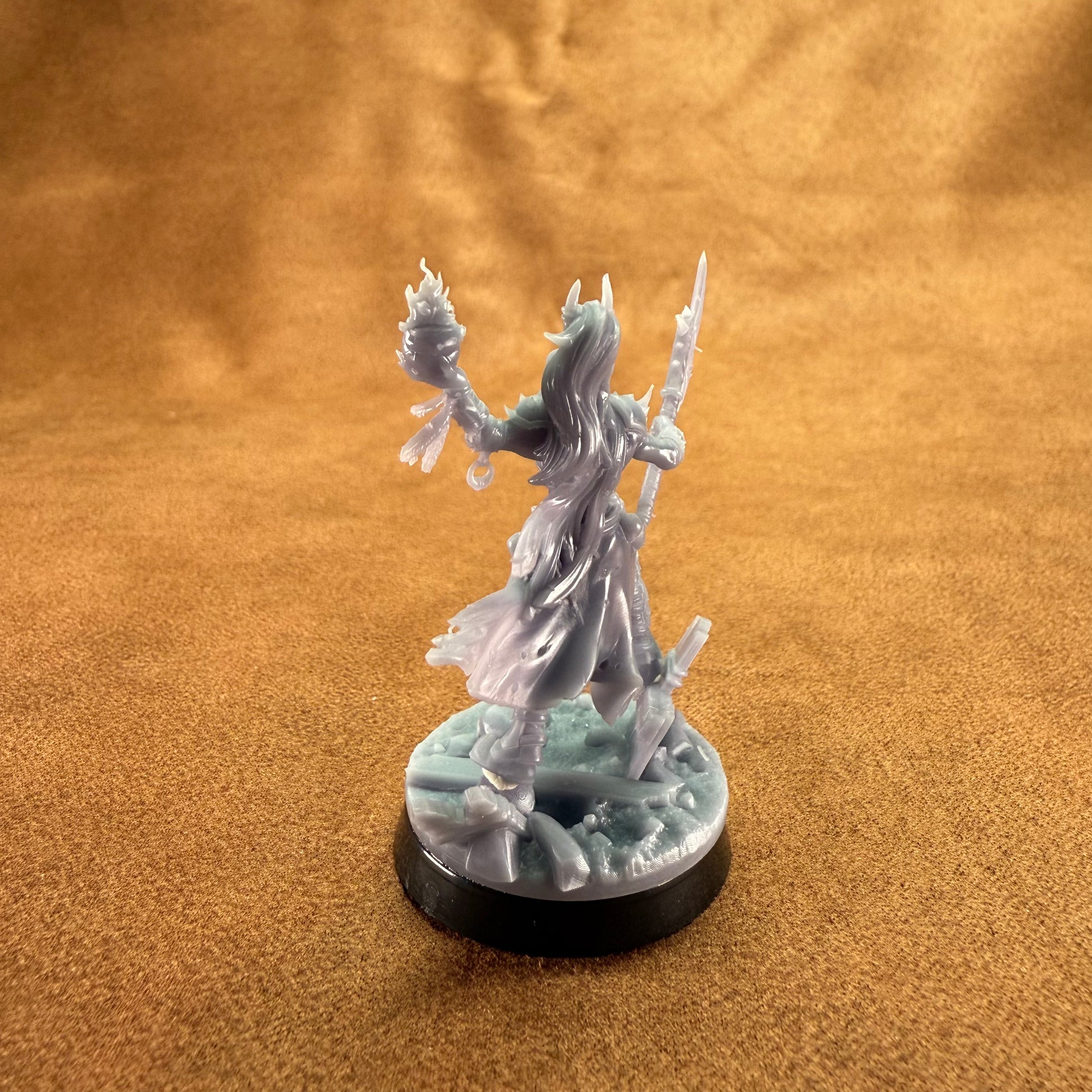 Fantasy figurine on a round base against a brown fabric background