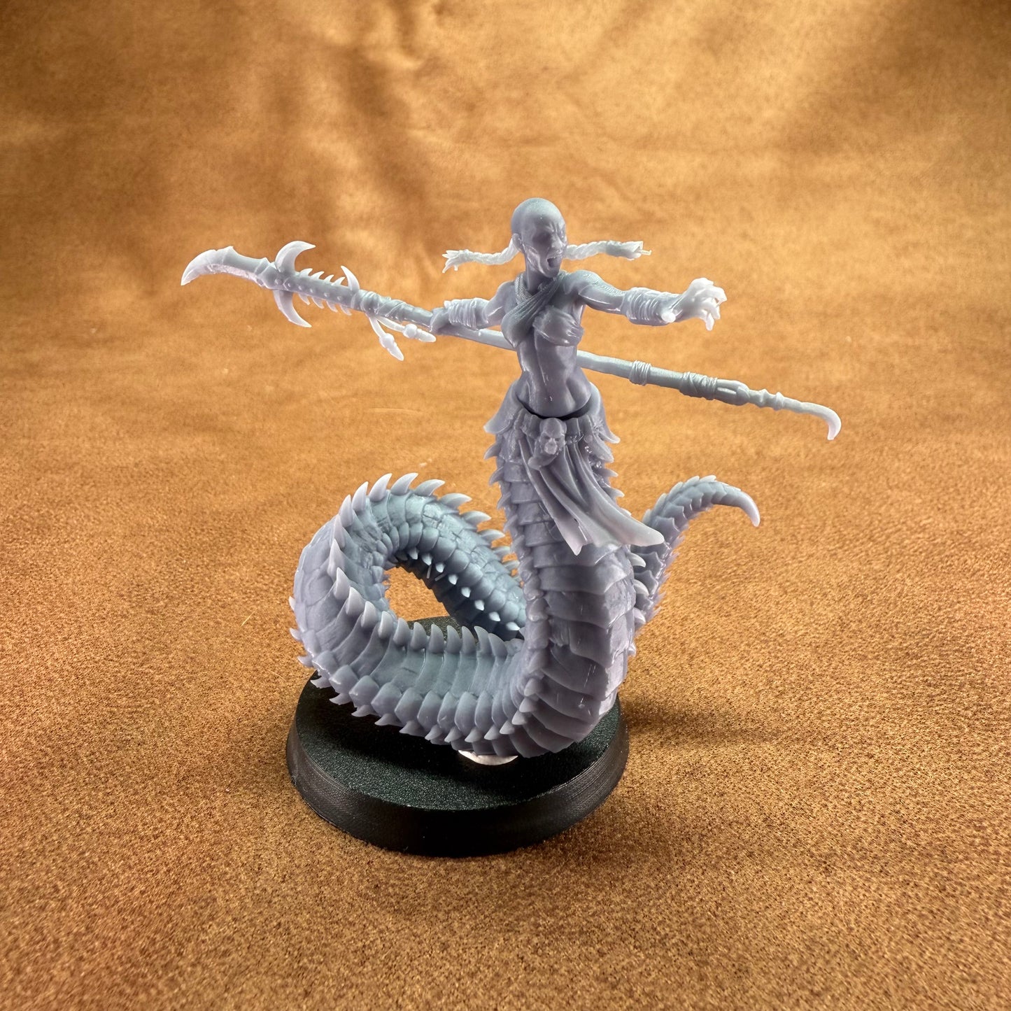 Gray fantasy figurine with a dragon-like creature on a brown surface