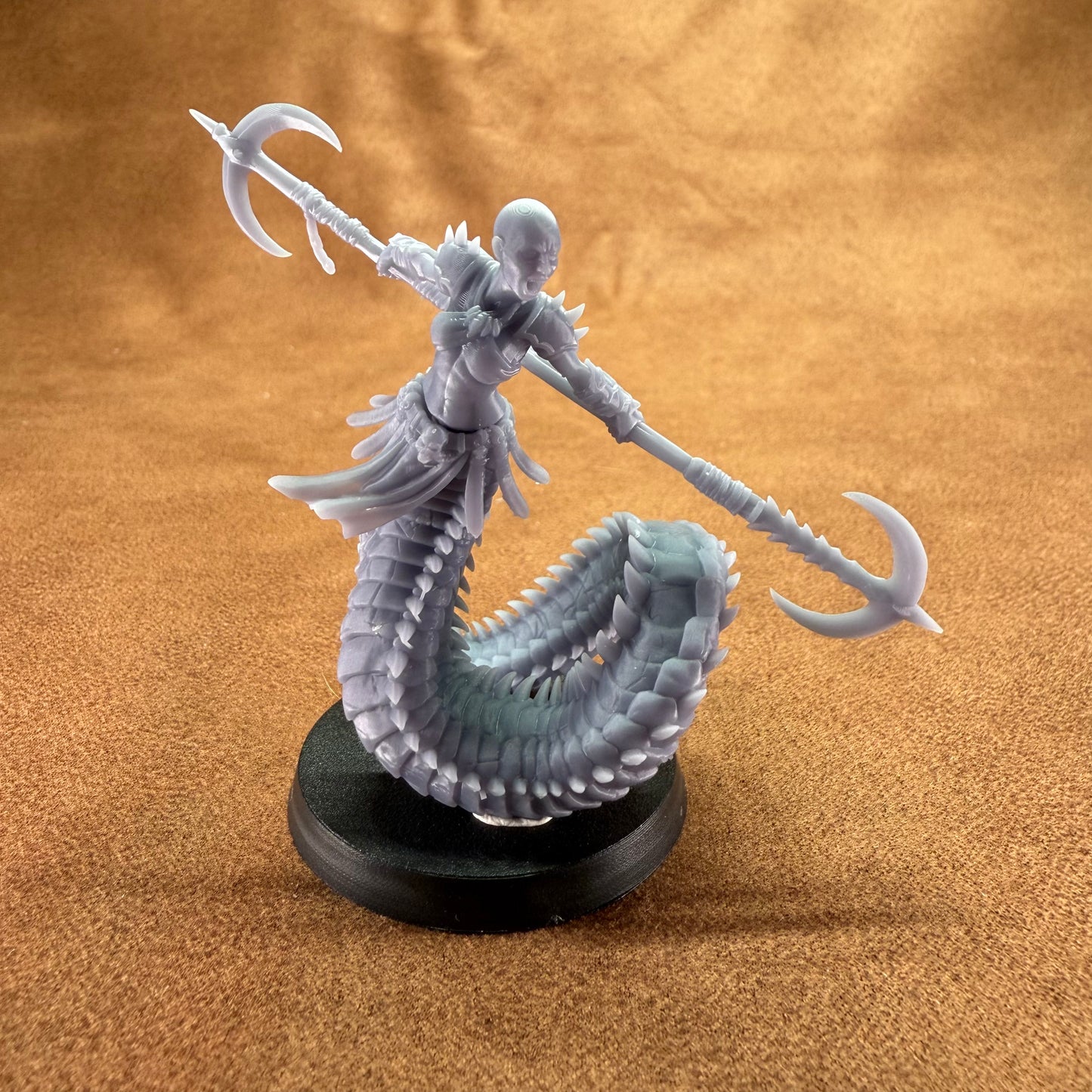 Fantasy figurine with a serpent-like creature and spear on a brown background