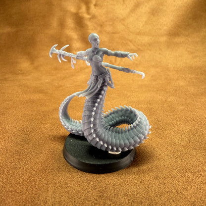 Figurine of a creature with a snake-like body and humanoid upper body on a brown surface