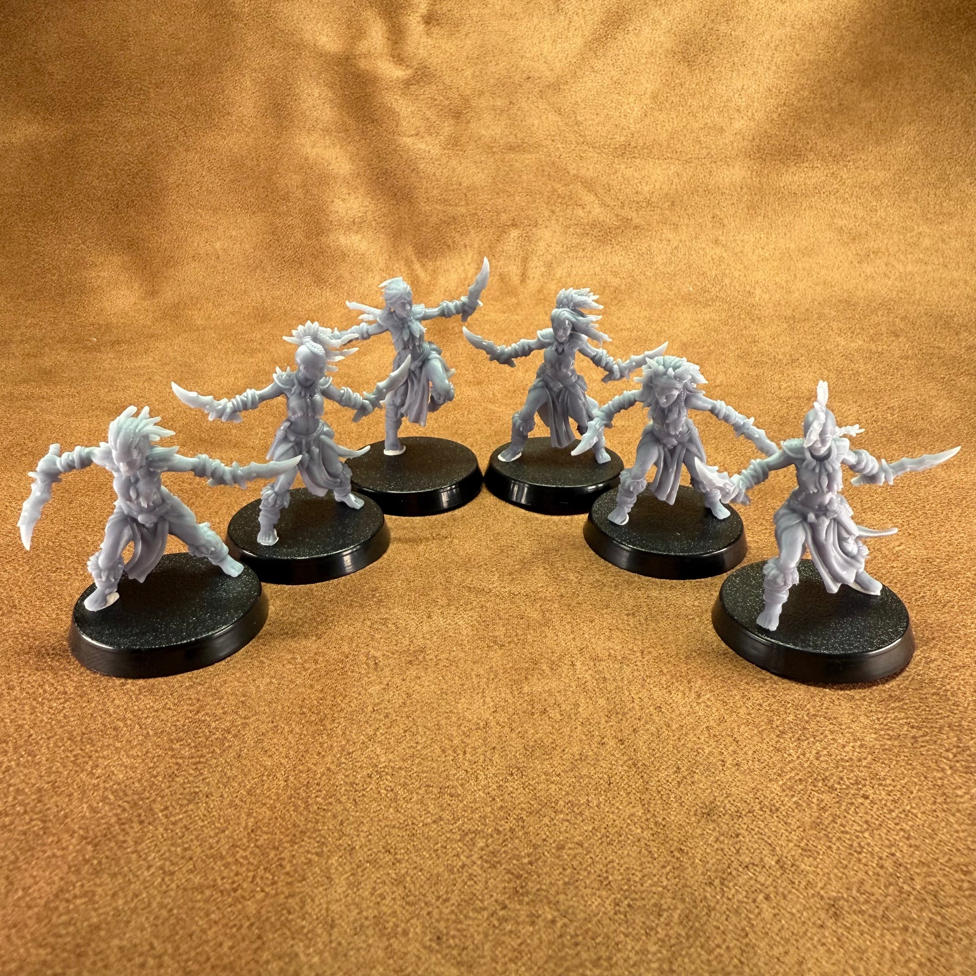 Six fantasy miniature figures on black round bases against a brown background