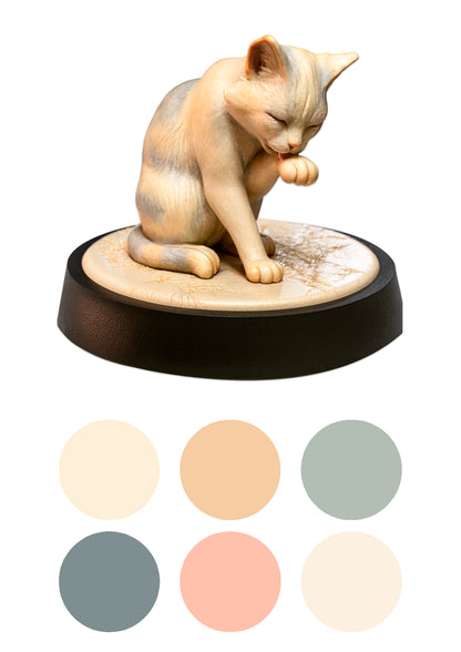 a cat licking its paw on a black base with colour swatches beneath it on a white background.