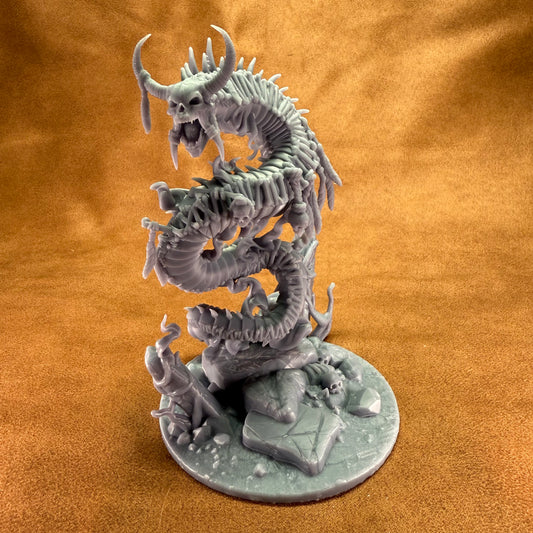 Gray dragon figurine on a round base against an orange background