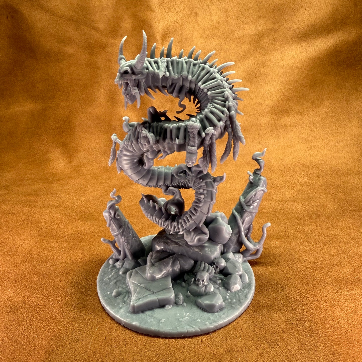 Dragon-like creature figurine on a round base against a brown background