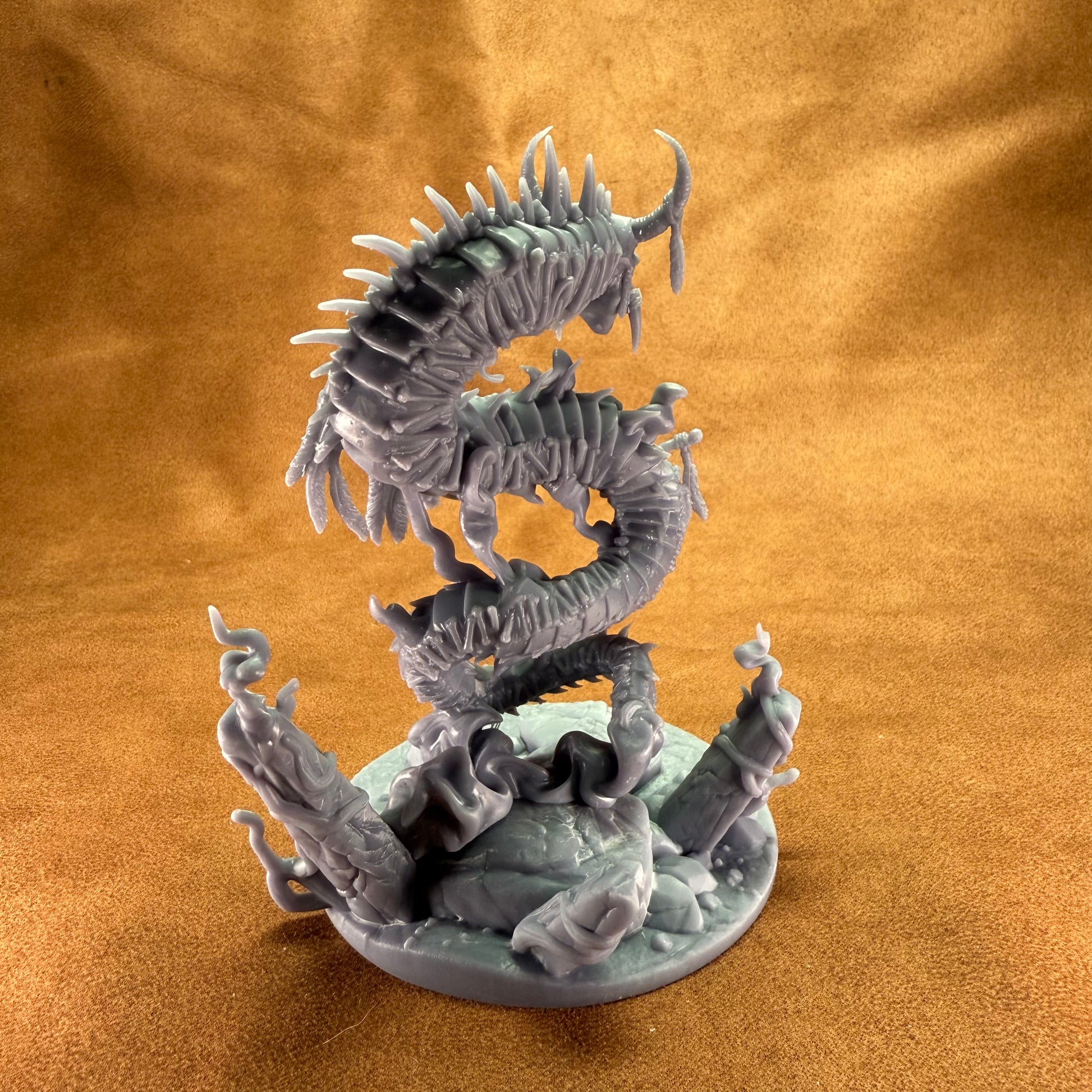 Dragon-like creature figurine on a round base against a brown background