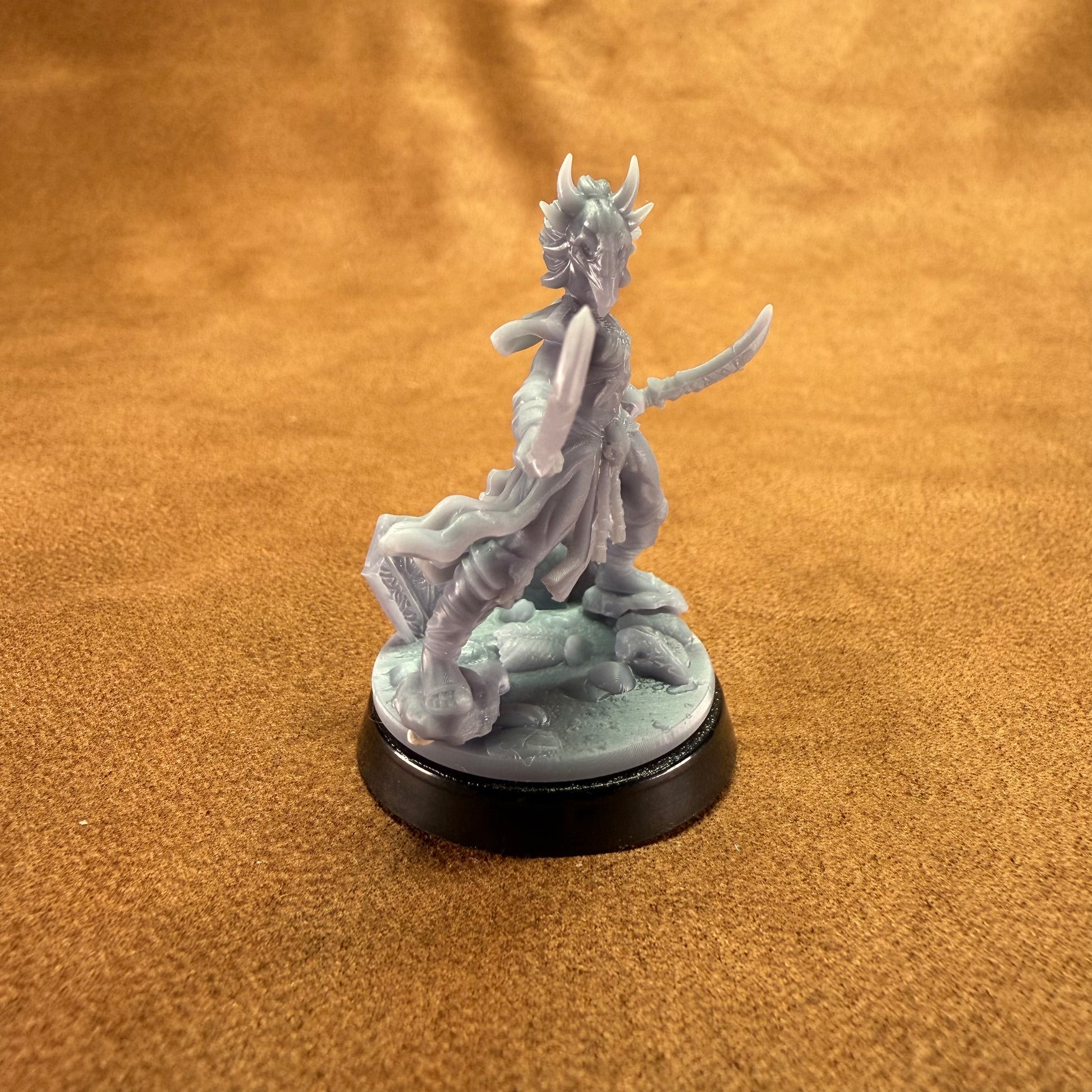Gray fantasy figurine on a black base against an orange fabric background