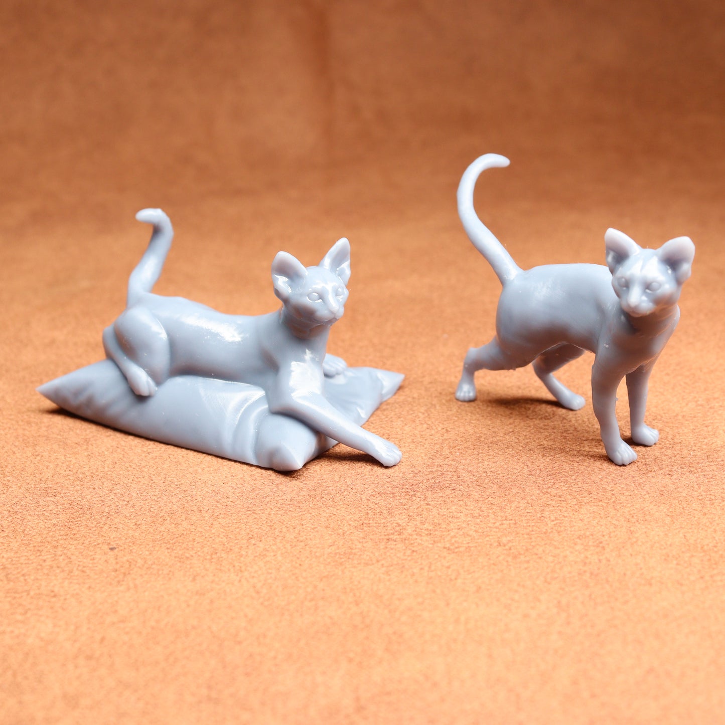 Two white cat figurines on a brown surface