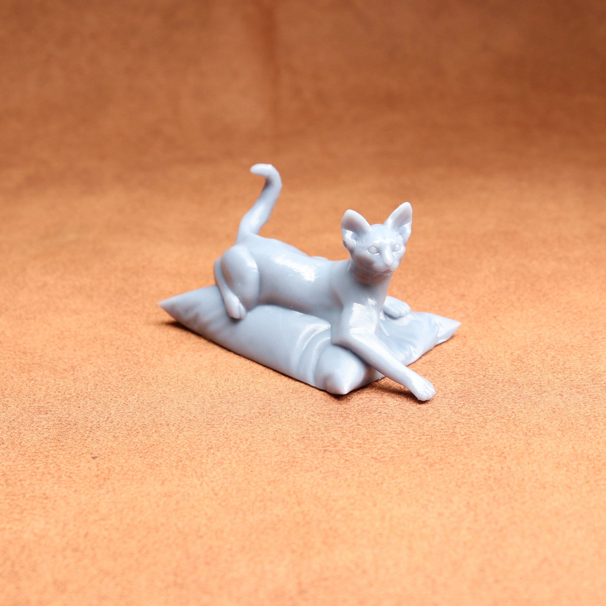 White cat figurine lying on a pillow against an orange background