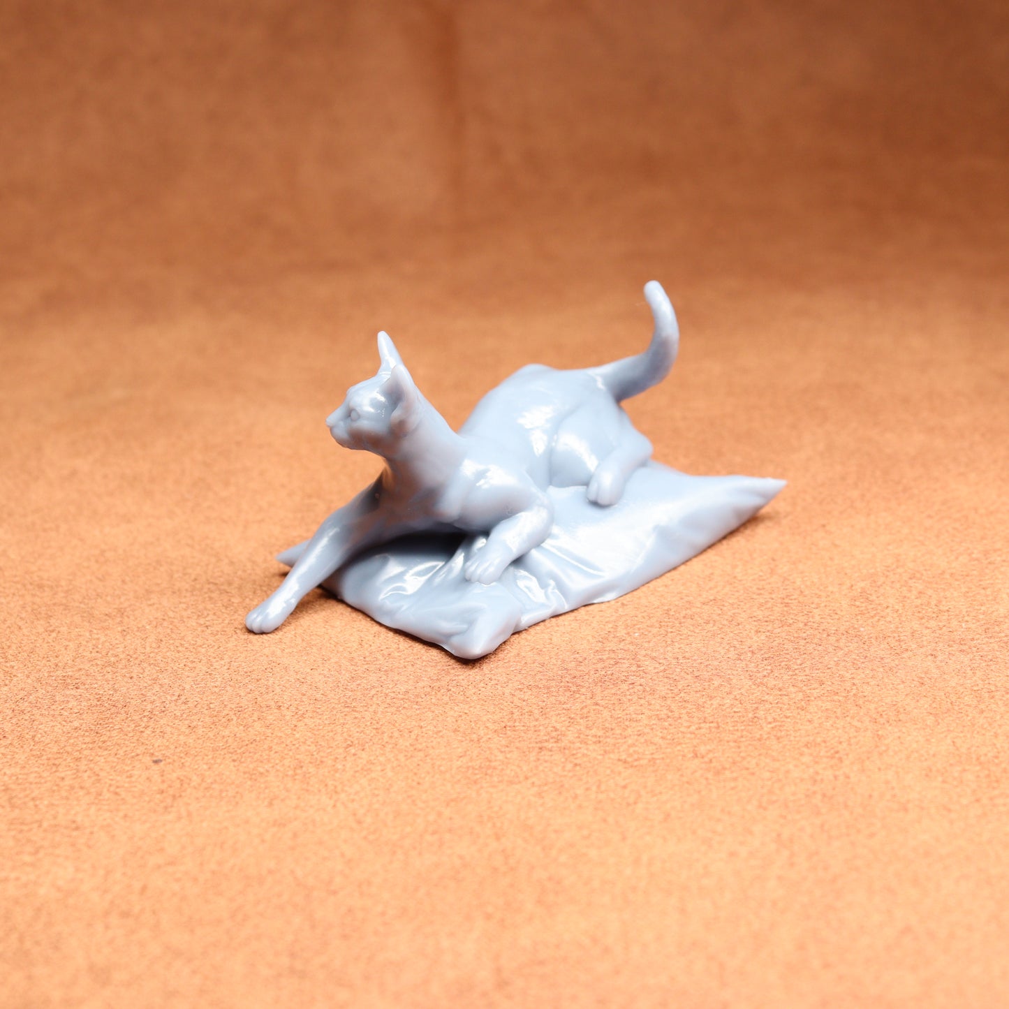 White ceramic sculpture of a cat on a textured brown surface