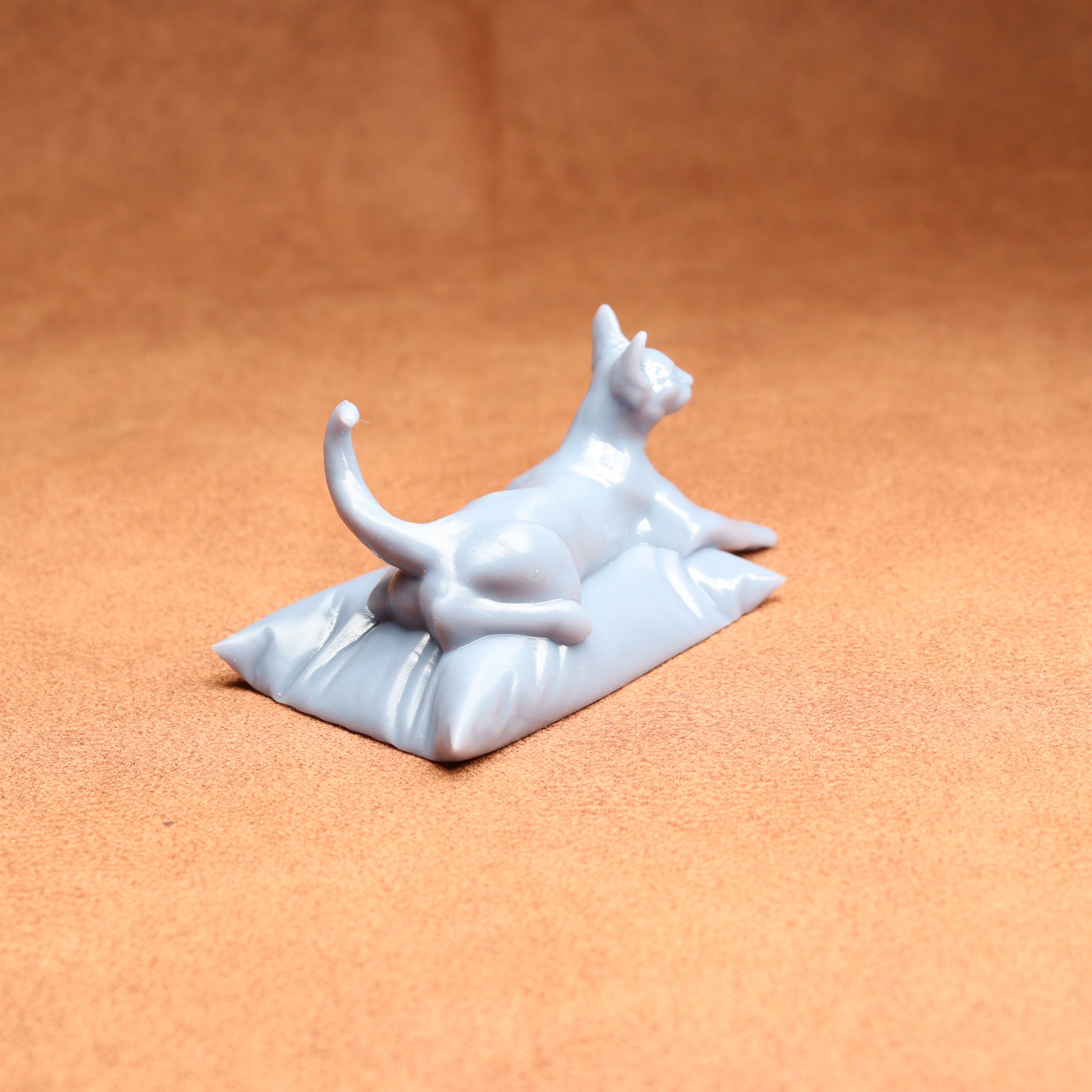 White ceramic cat figurine on a small white base against an orange background