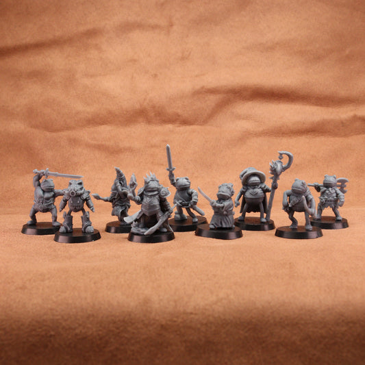 A set of unpainted gray fantasy tabletop miniatures posed in a row on a brown textured fabric background.