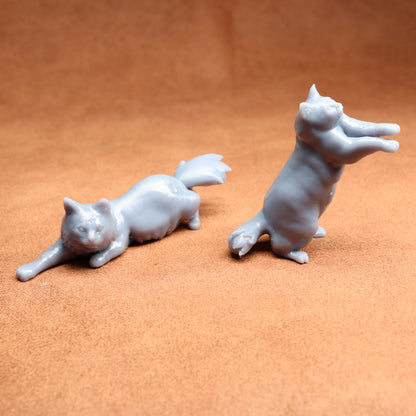 Two white cat figurines on a brown surface