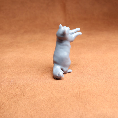 White ceramic cat figurine on a brown surface