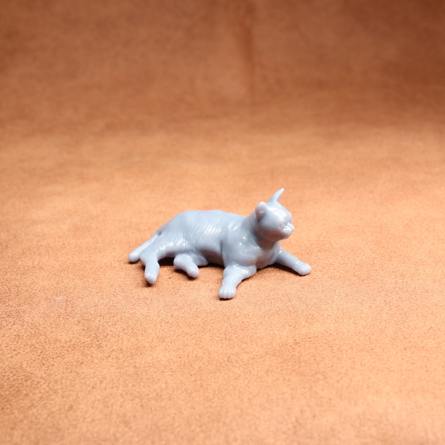 Small gray cat figurine on a brown surface
