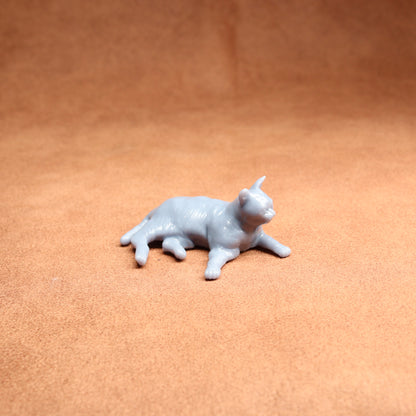 Small gray cat figurine on a brown surface
