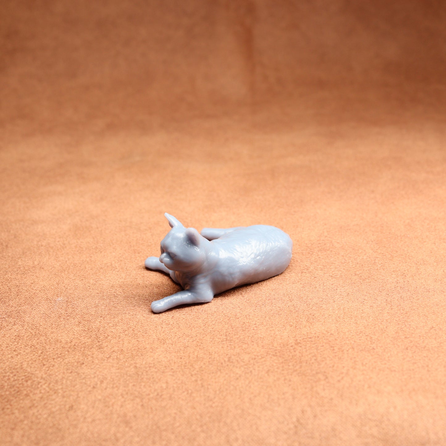 Small white ceramic cat figurine on a brown surface